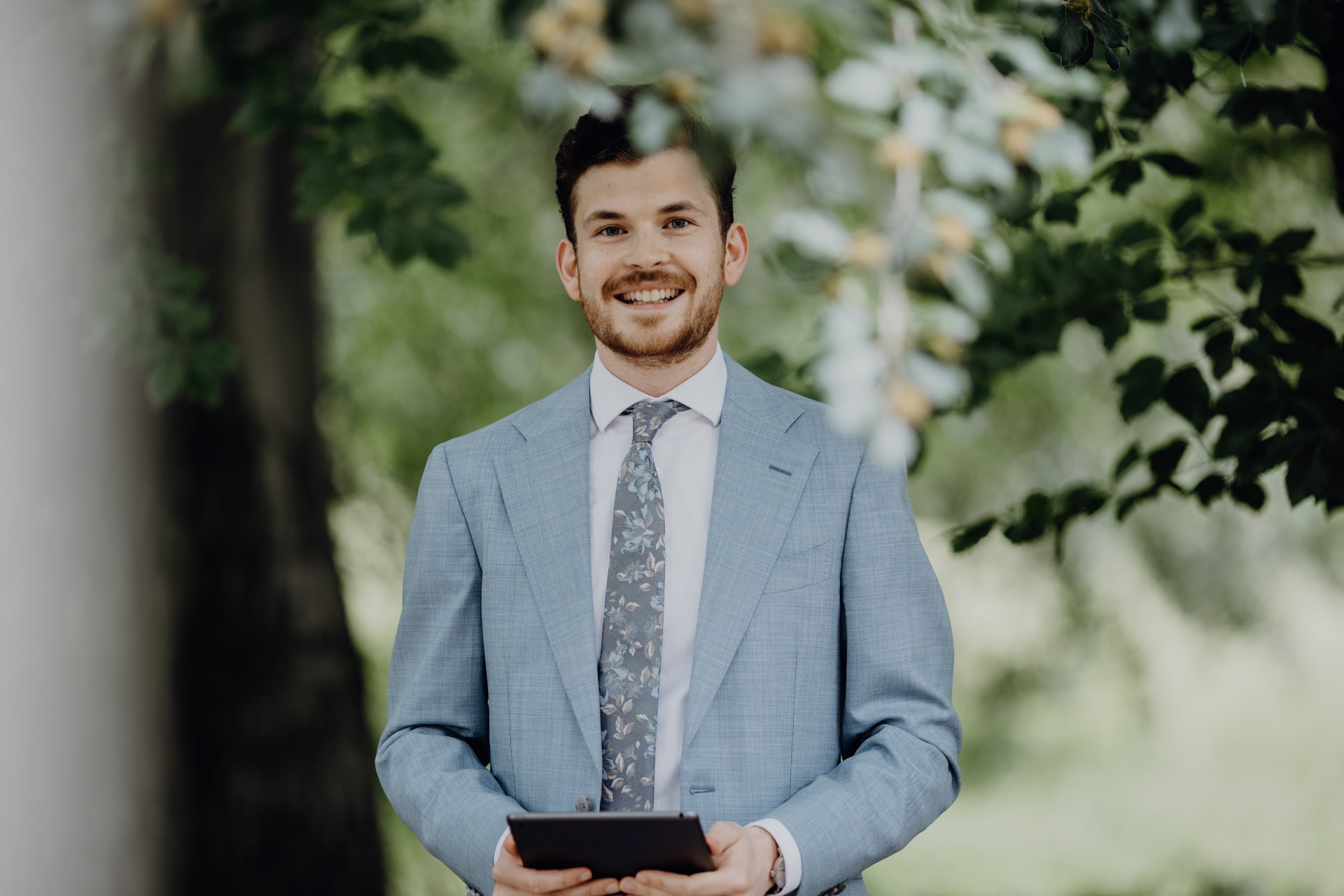 Luca Würz als Trauredner mit Tablet unter einem Baum